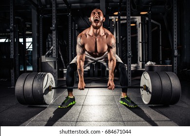 Muscular men lifting deadlift In the gym