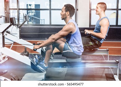 Muscular Men Using Rowing Machine At Gym