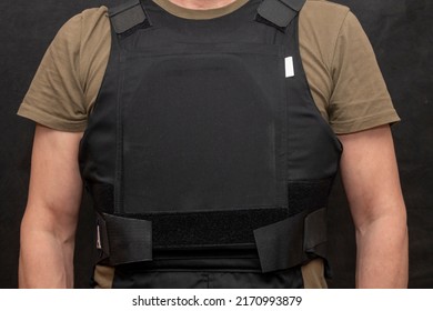 Un militar muscular en un chaleco antibalas sobre un fondo negro.