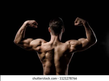 Muscular Model Sports Young Man On A Dark Background. Sporty Healthy Strong Muscle Guy Showing His Back And 
Big Shoulders,biceps, Triceps. Sexy Male Flexing His Muscles. Workout Bodybuilding Concept.