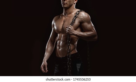Muscular model sports young man on dark background. Fashion portrait of strong brutal guy with chain. Sexy torso. Male flexing his muscles. Sport workout bodybuilding concept.