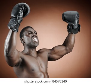 Muscular serious looking boxer raises his gloved arms