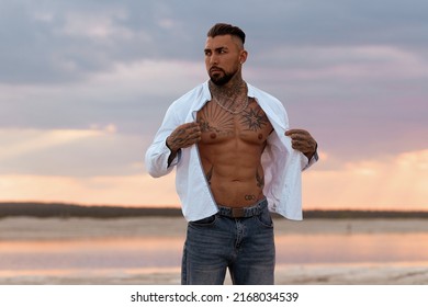 Muscular Sexy Young Man Taking Off T Shirt On Empty White Sand Beach And Turquoise Ocean. Sexy Summer Love.