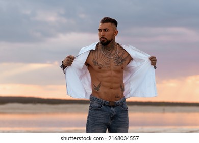 Muscular Sexy Young Man Taking Off T Shirt On Empty White Sand Beach And Turquoise Ocean. Sexy Summer Love.