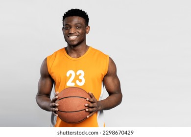 Muscular smiling African American man playing basketball, holding ball looking at camera, isolated on white background, copy space - Powered by Shutterstock