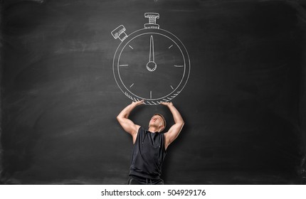 A Muscular Sportsman Holding Up A Big Timer, Drawn On The Blackboard. Time Management. Sport And Fitness. Poses And Gestures.