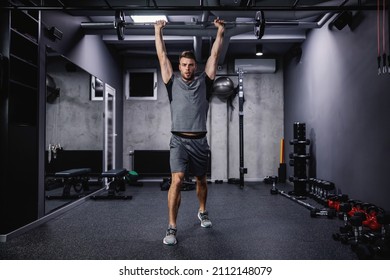 A muscular sportsman lifting weights in a gym.