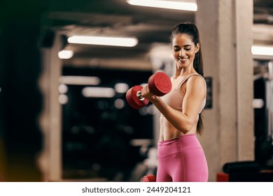 A muscular sportswoman is doing dumbbells curls in a gym and flexing muscles. - Powered by Shutterstock