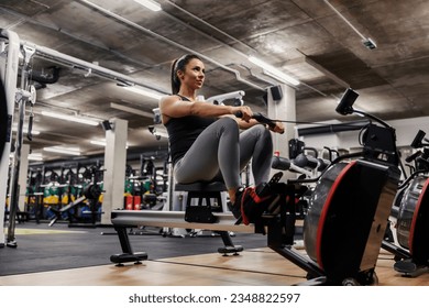 Una deportista muscular en forma está haciendo ejercicios en una máquina de remo.