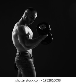 Muscular Strong Men, Bodybuilder Is Working Out, Lifting Dumbbells, Doing Exercises For Biceps Looking At It In Gym Over Dark Back Ground With Copy Space. Young Man Lifting Weights. Black And White 