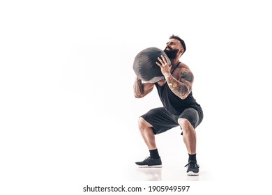 Muscular Tattooed Bearded Male Exercising Fitness Weights Medicine Ball In Studio Isolated On White Background.