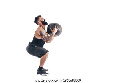 Muscular Tattooed Bearded Male Exercising Fitness Weights Medicine Ball In Studio Isolated On White Background.