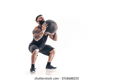 Muscular Tattooed Bearded Male Exercising Fitness Weights Medicine Ball In Studio Isolated On White Background.