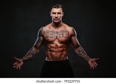 A Muscular Tattooed Man On A Dark Background.