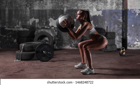 Muscular woman doing intense squats with medicine ball in gym. - Shutterstock ID 1468248722
