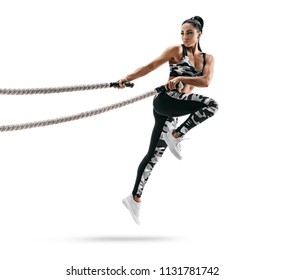 Muscular woman jumping with heavy ropes. Photo of latin woman in military sportswear isolated on white background. Strength and motivation.