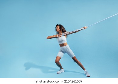 Muscular Woman Pulling Resistance Band. Young Female In Sportswear Doing Intense Exercises With Elastic Band.