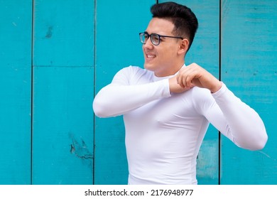 A Muscular Young Athlete With An Injured Shoulder Complains Of Pain. A Man With Nearsightedness Wears Glasses. Isolated On Sky Blue Background