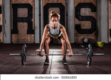 Muscular young fitness woman doing heavy  deadlift exercise in gym