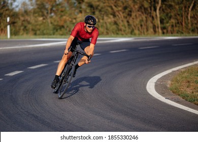 Un joven musculoso con ropa deportiva, casco protector y gafas espejadas disfrutando de la actividad deportiva en bicicleta negra. Alta velocidad y carreras.