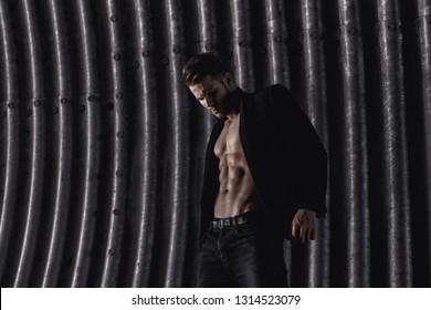 Muscular young man with beard on dark tunnel urban background. Fashion portrait of brutal strong muscle guy with modern trendy hairstyle. Model, fashion concept. Sexy naked torso, six pack abs.