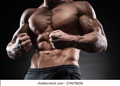 Muscular Young Man In Studio On Dark Background Shows The Different Movements And Body Parts