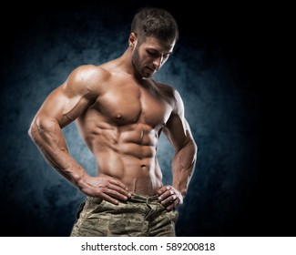 Muscular Young Man In Studio On Dark Background Shows The Different Movements And Body Parts