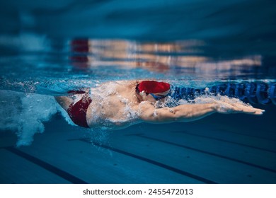 Muscular young man, swimmer in motion, preparing for competition, training in swimming pool indoors. Speed and technique. Concept of professional sport, health, endurance, strength, active lifestyle - Powered by Shutterstock