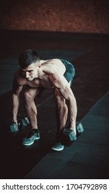 Muscular Young Man Training Burpee With Dumbbells On The Gym Floor