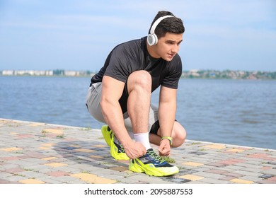 Muscular Young Man Tying Shoe Lace Near River