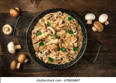 Mushroom beef stroganoff, with cremini and champignons, in a frying pan, shot from above on a dark rustic texture with a place for text