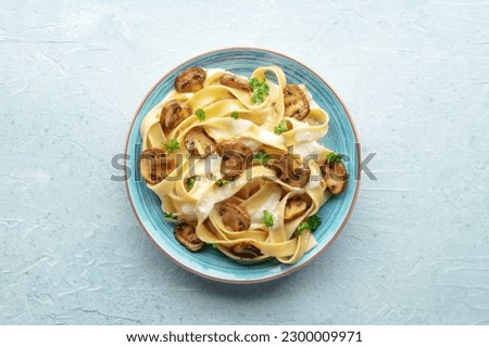Mushroom pasta, pappardelle with cream sauce and parsley, overhead flat lay shot on a stone background