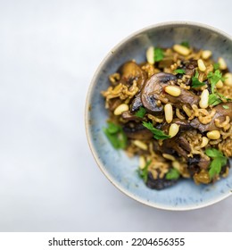 A Mushroom Pilaf With Pine Nuts And Coriander In A Blue Bowl. A Plant-based Healthy Vegan Meal. Beautiful Food Photography.