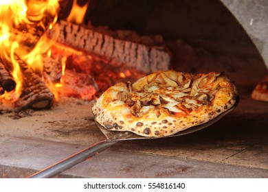 Mushroom pizza being pulled from mobile wood fired oven food truck at a catering event