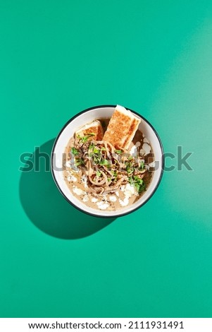 Mushroom soup with bread on green background. Autumn soup in minimal style. Creamy mushroom soup in bowl in modern concept. Colour background and hard shadow in food menu