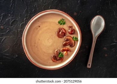 Mushroom Soup, Garnished With Parsley, Overhead Shot On A Black Slate Background With A Spoon