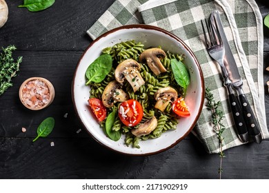 Mushroom and Spinach Pasta in a Bowl, Vegan Food on dark background. Vegan or gluten free diet. banner, menu recipe place for text, top view.