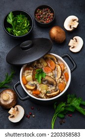 Mushrooms And Barley Soup In Pot, Top View, Black Background