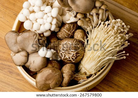 Mushrooms. Fresh Organic, enoki, shiitaki, hen of the woods, baby portabello, button mushrooms in wooden woven basket at a restaurant. Variety of Mushrooms in a basket, closeup and shot overhead.