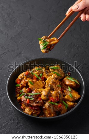 Mushrooms Manchurian dry in black bowl at dark slate background. Mushroom Manchurian - is indo chinese cuisine dish with deep fried mushrooms, bell peppers, sauce and onion.