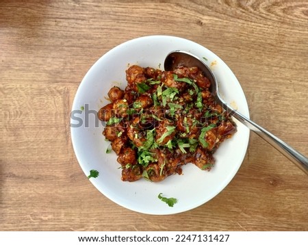 Mushrooms Manchurian dry in a white plate, Mushroom Manchurian - is indo chinese cuisine dish with deep fried mushrooms, bell peppers, sauce and onion 