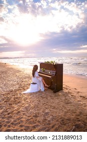 Music background.Melody and song concept in nature.Surreal image of grand piano in scenic sunset beach. Woman playing the piano