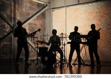Music band and fashion. Handsome young men in suits playing rock and singing song. Bands silhouettes with on a concert.