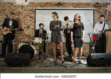 Music Band Of Six People (two Women, Four Men) Performs On Stage In Club