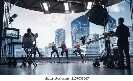 Music Clip Studio Set: Shooting Hip Hop Video Dance Scene with Three Professionals Dancers Performing on Stage with Big Led Screen with Modern City Background. Director and Cameraman in Backstage. - Shutterstock ID 2139038867