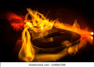 Music concept. Acoustic guitar on a dark background under beam of light with smoke with copy space. Exploding guitar. Fire effects. Surreal guitar. Selective focus