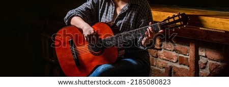 Music concept. Girl guitarist plays. Girl play the guitar. Woman hipster man sitting in a pub. Woman playing guitar, holding an acoustic guitar in his hands.