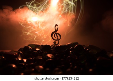 Music concept. Musical symbol treble clef stainless steel miniature with colorful toned light on foggy background. Selective focus