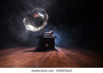 Concepto musical. Viejo gramófono sobre un fondo oscuro. Grópico retro con disco sobre mesa de madera con luz de fondo tonificada. Enfoque selectivo