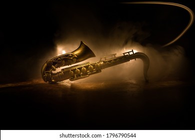 Music concept. Saxophone jazz instrument. Alto gold sax miniature with colorful toned light on foggy background. Saxophone music instrument in lowlight. Selective focus